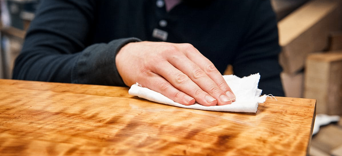 Craftsman applying hand-rubbed finish to fine wood furniture